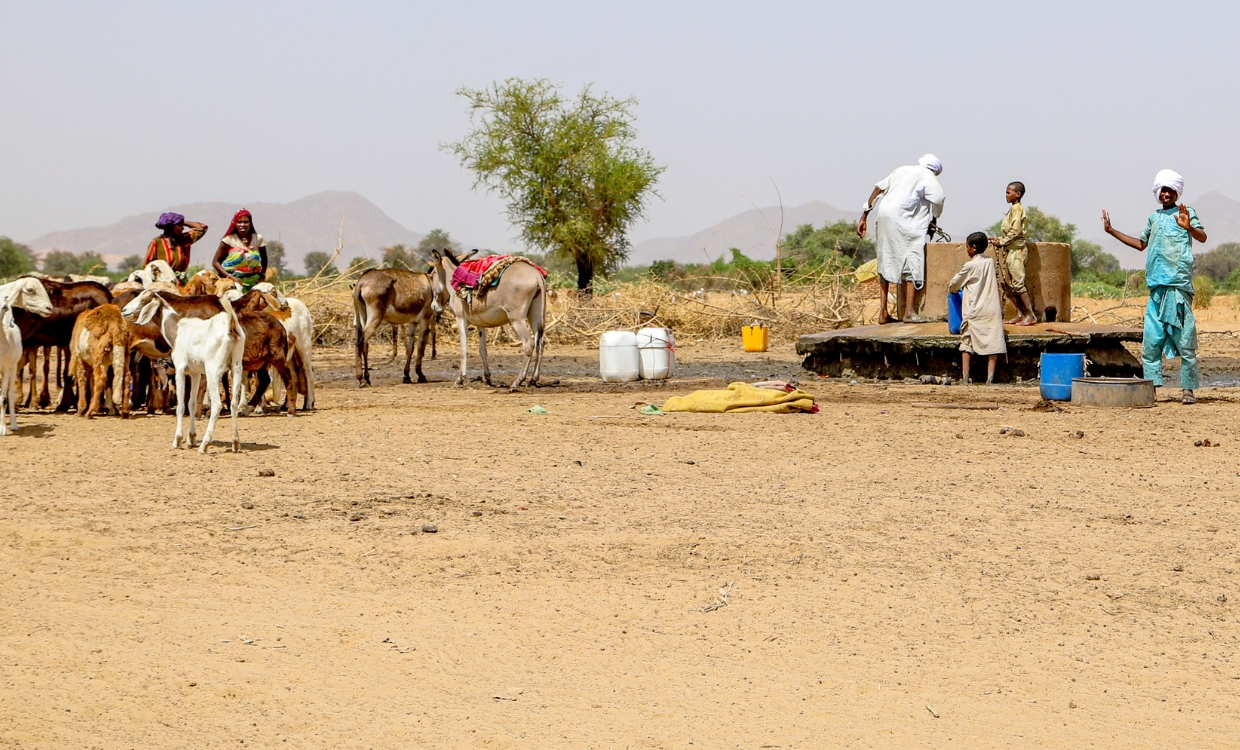 Menschen schöpfen Wasser an einer Wasserstelle.