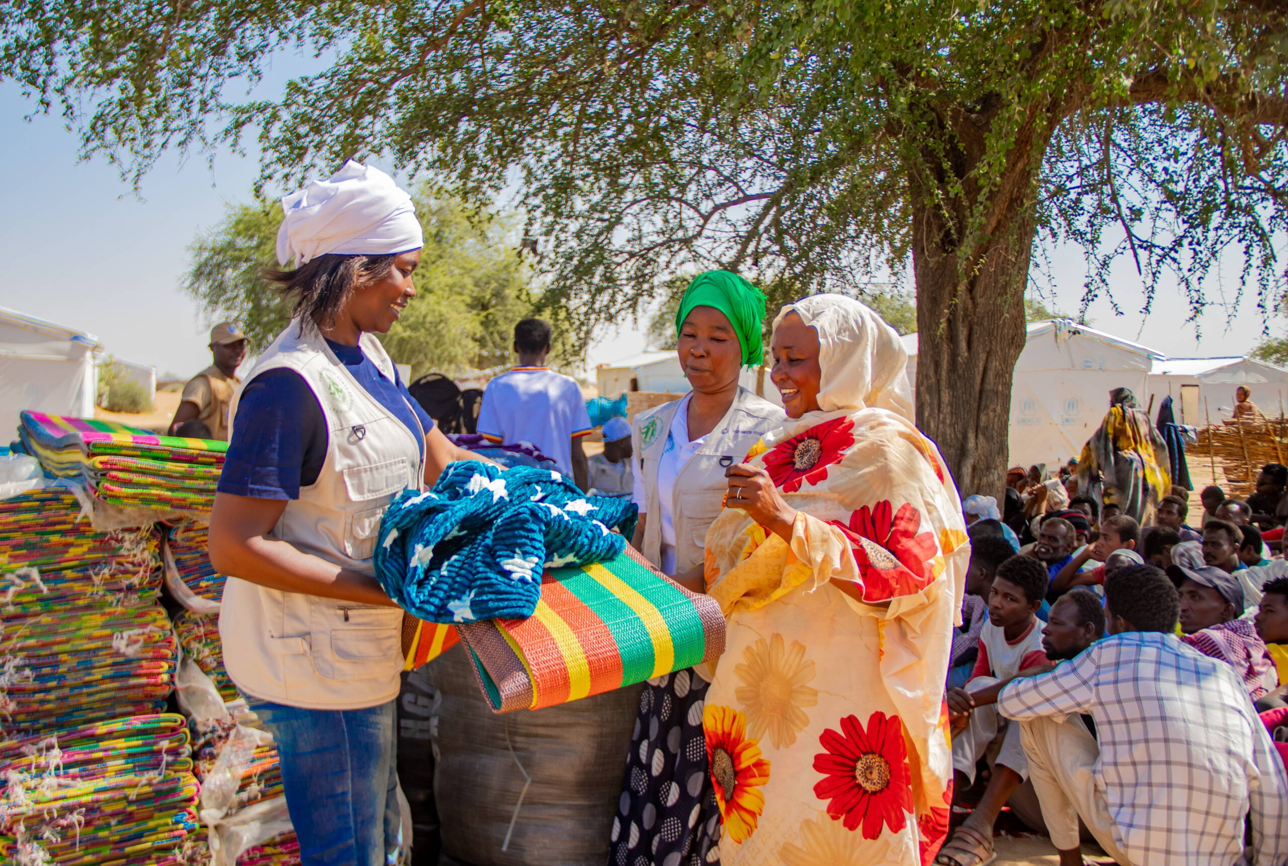 Zwei Frauen verteilen Decken und Matten.