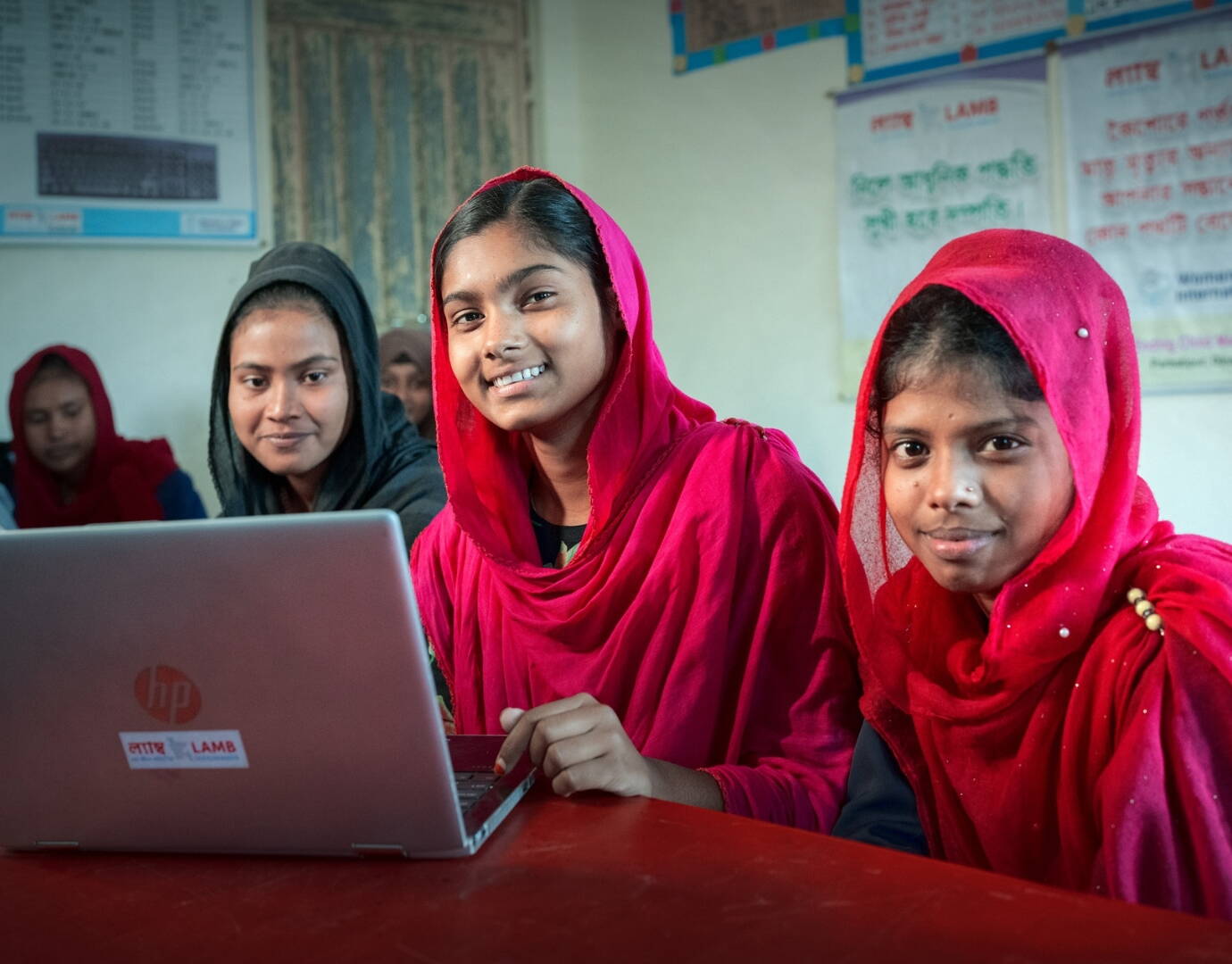 Jetzt spenden! Mädchen sitzen stolz hinter einem Laptop.